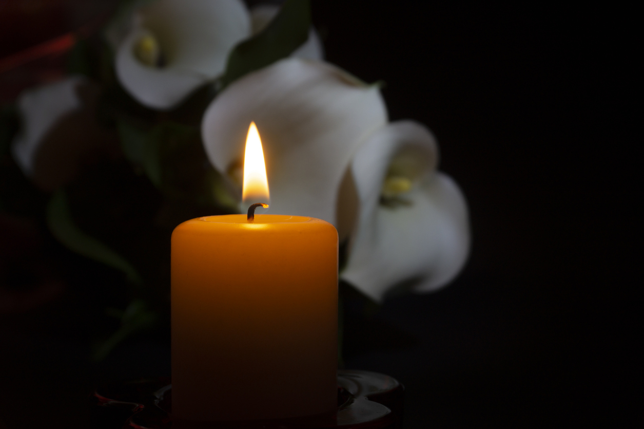 Close up of orange candle flame and lily flowers representing a wrongful death accident