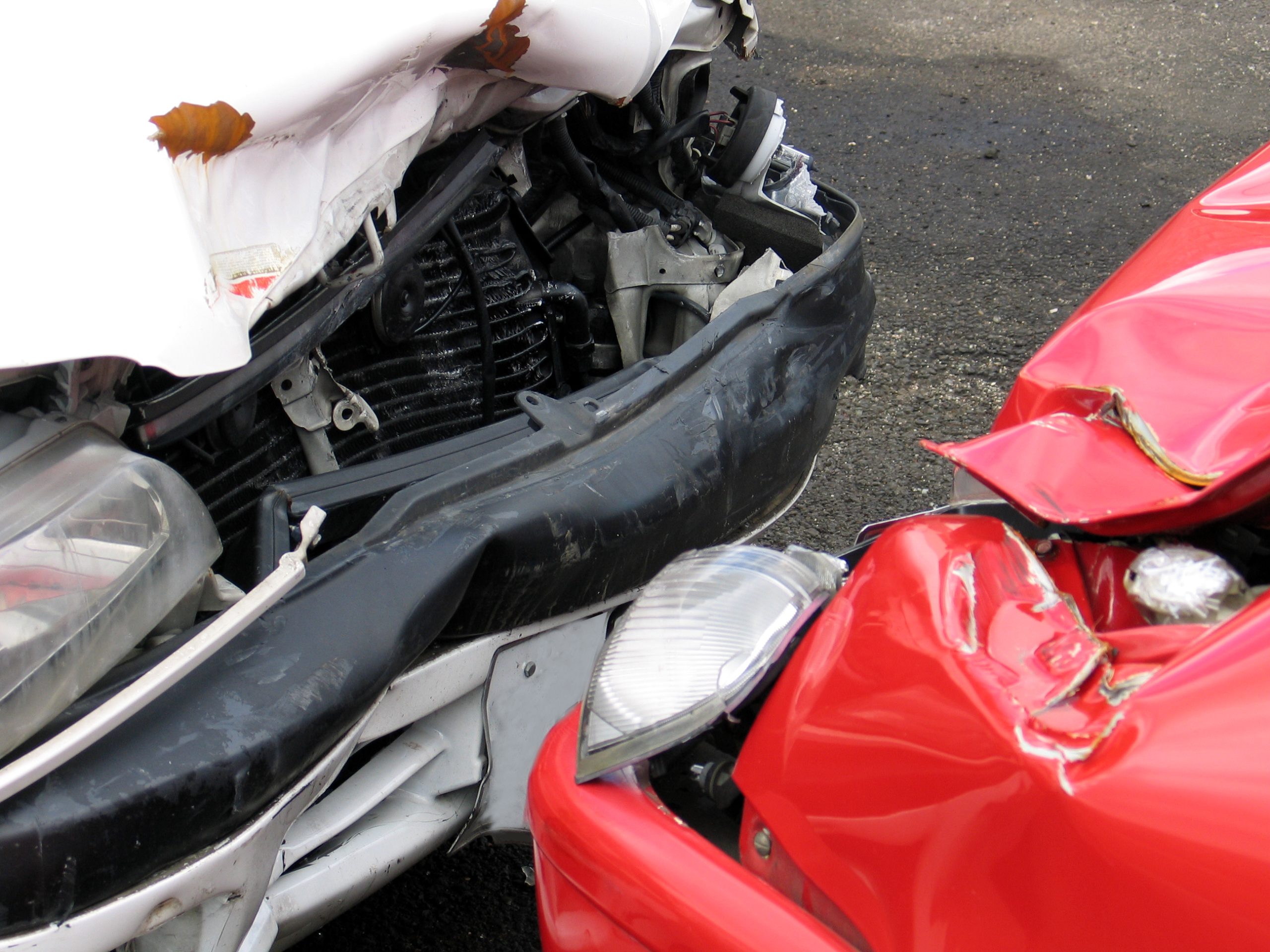 A close up of the front ends of two cars that have been in a head-on collision