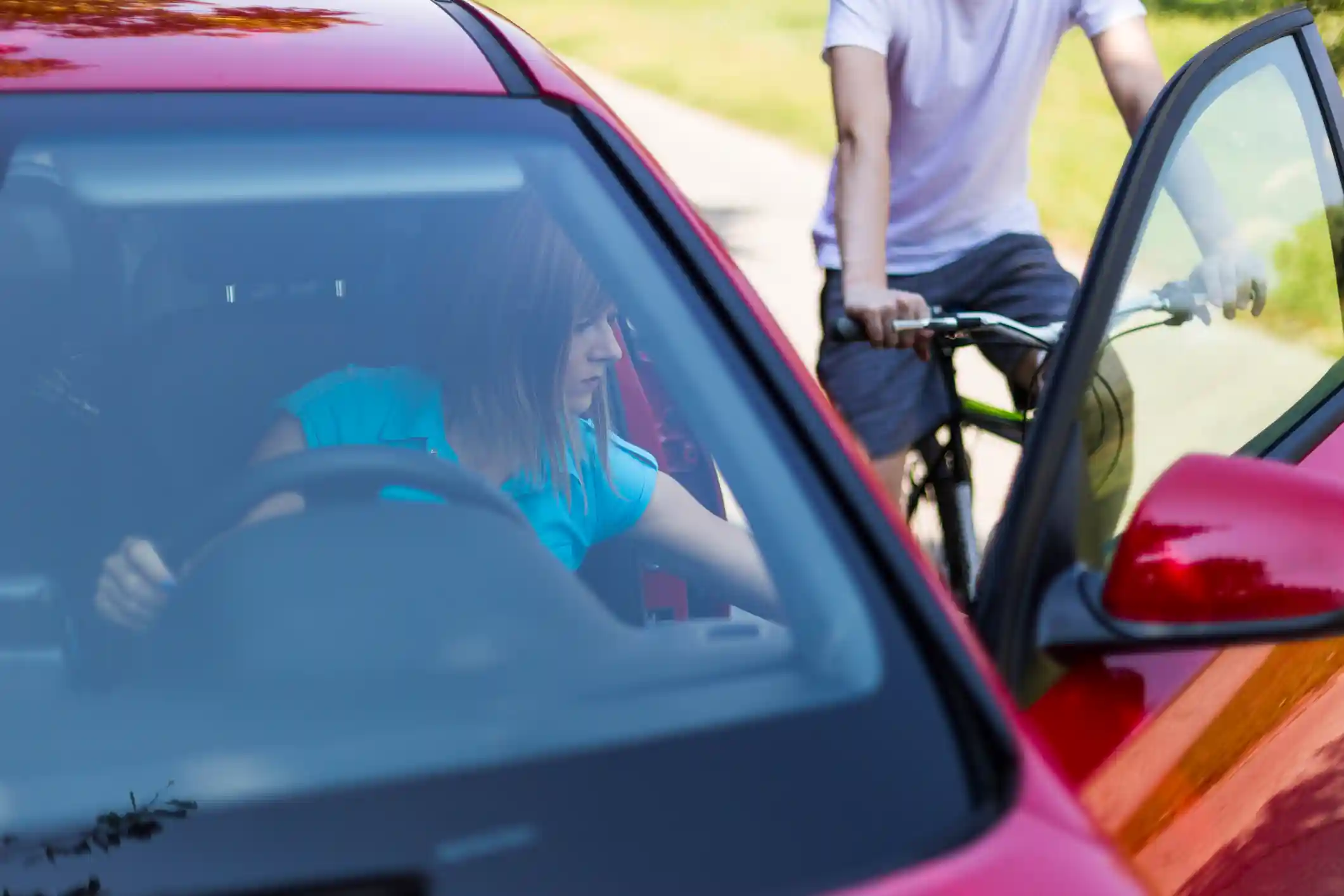 A woman opening a door in front of a bicyclist, leading to a dooring bicycle accident