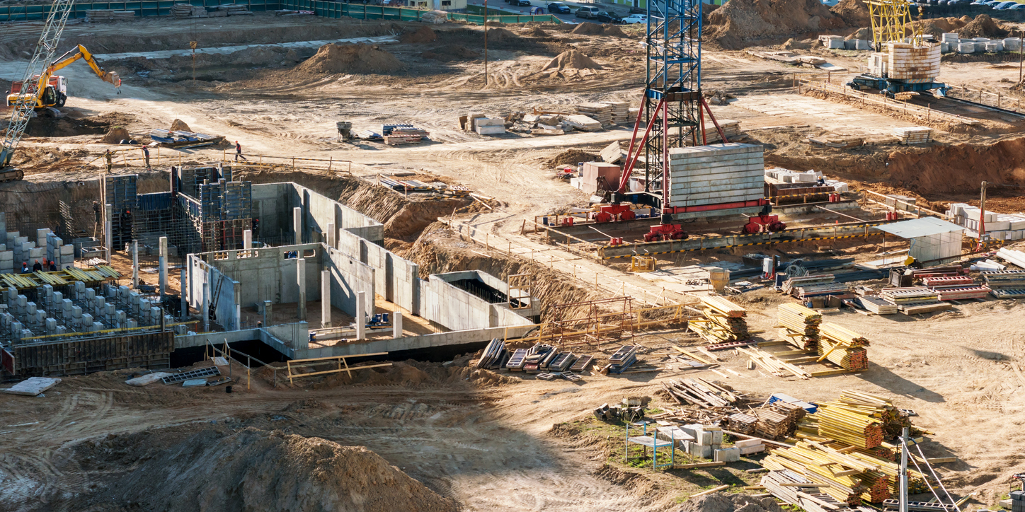 Aerial view of a large construction site where workers are pouring a concrete foundation