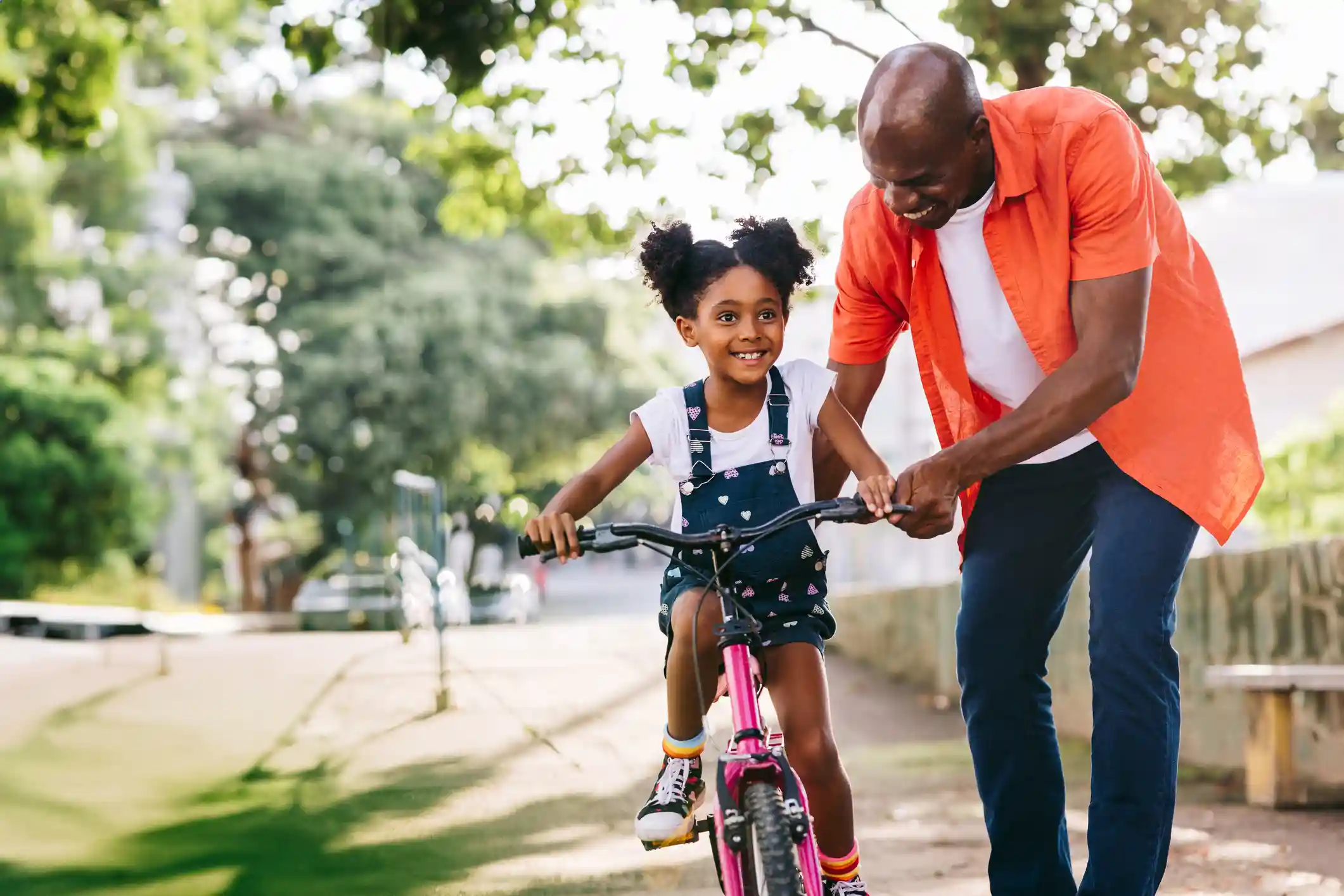 A father teaching his young daughter how to ride a bike